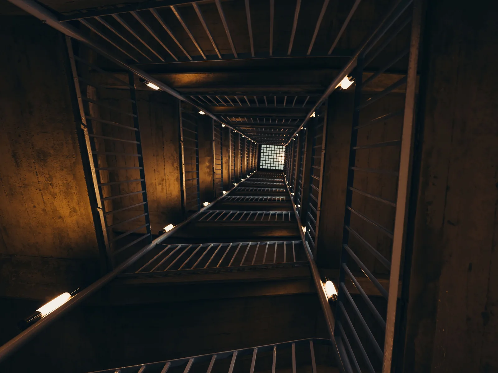 Hueco de escalera de un edificio antiguo con una luminaria encendida en cada rellano