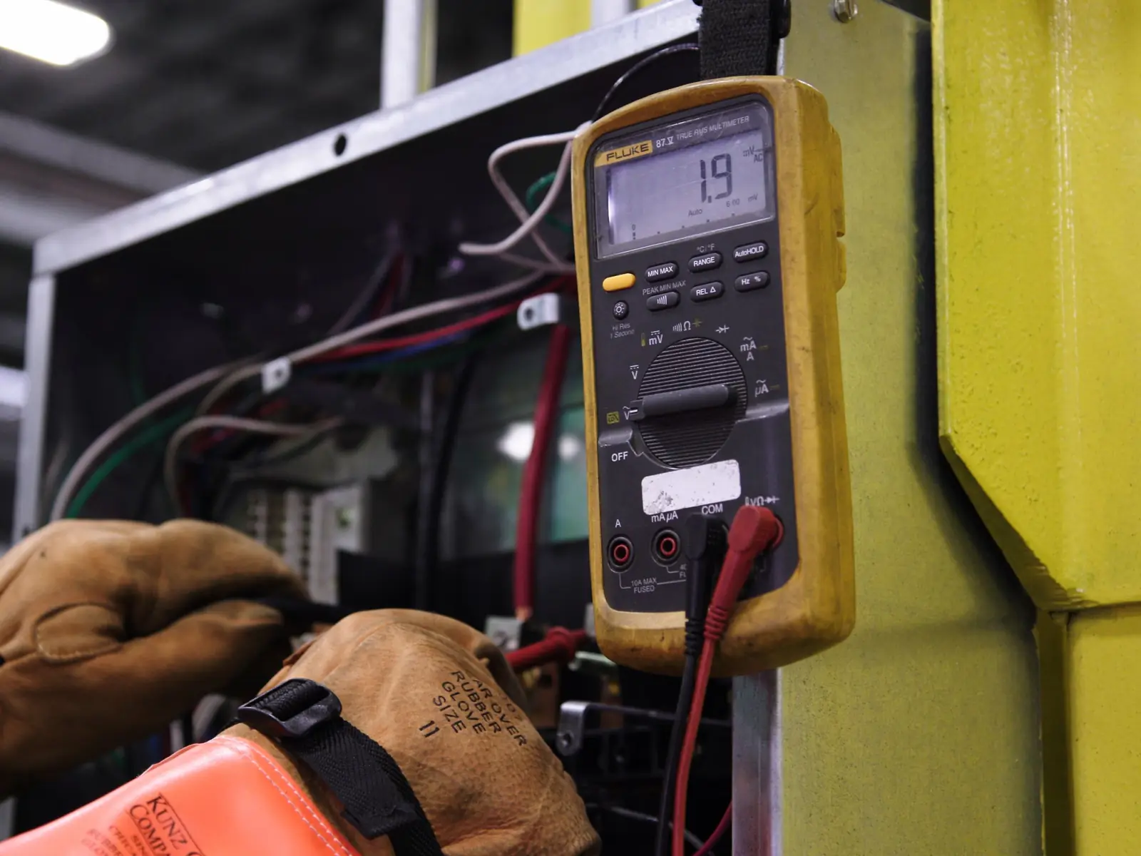Electricista midiendo con el polímetro en un cuadro eléctrico abierto
