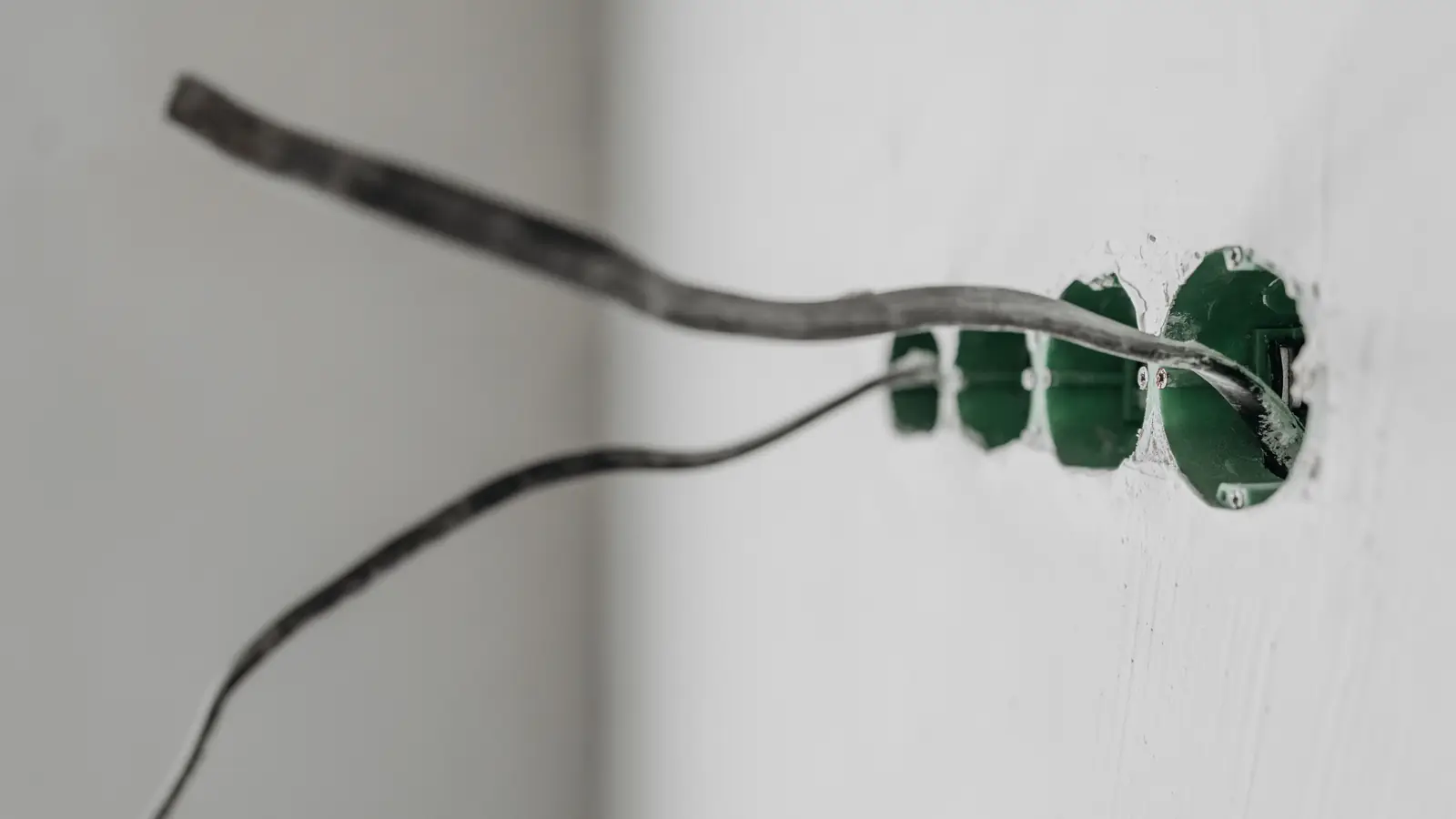 Manguera eléctrica tendida sobre una pared blanca hasta un grupo de cajas de registro