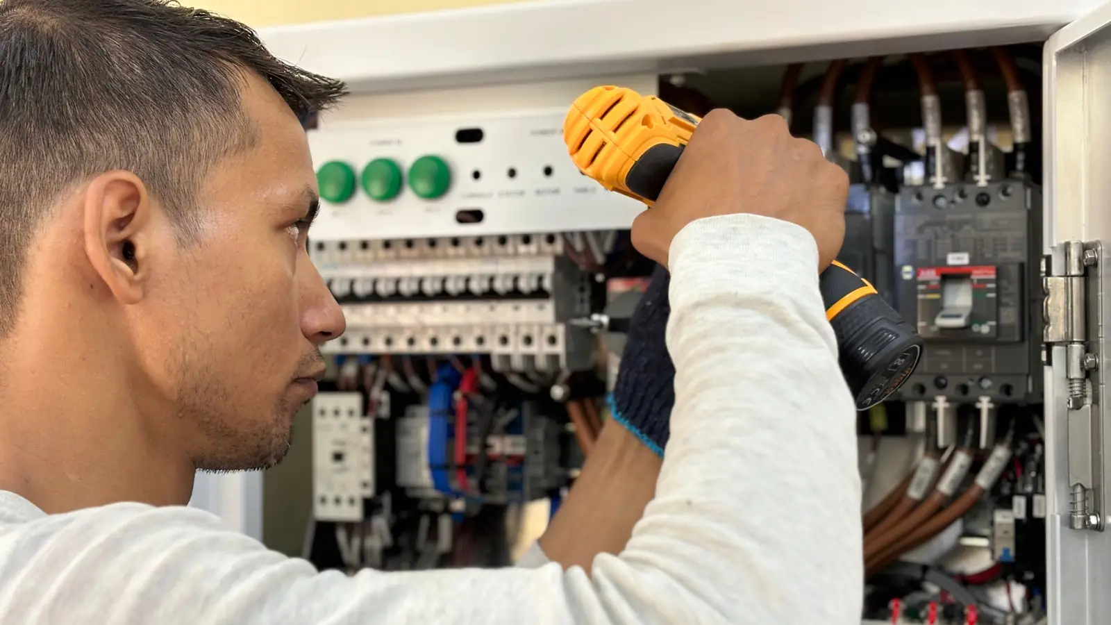 Electricista apretando bornes en un cuadro eléctrico abierto durante una avería